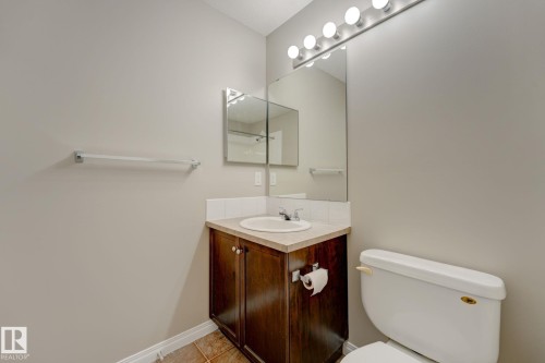 Bathroom featuring a dark wood-finish vanity with a built-in sink, a light-toned countertop, and a tiled backsplash - 7226 7327 South Terwillegar Drive, Edmonton, AB - Indoor Photo Showing Bathroom