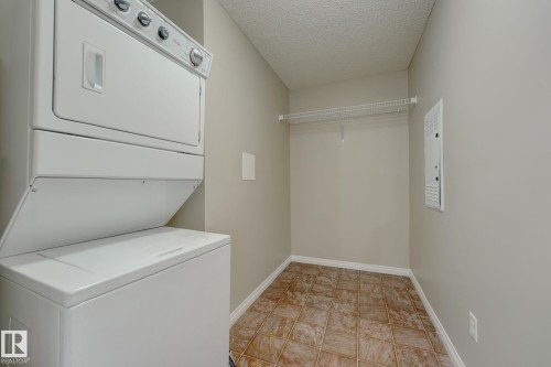 Laundry area featuring a stacked washer and dryer, tile flooring, and a wire shelving system - 7226 7327 South Terwillegar Drive, Edmonton, AB - Indoor Photo Showing Laundry Room