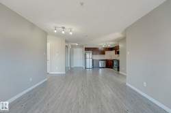 Open-concept living area featuring wood-finish flooring, neutral wall tones, and track lighting - 