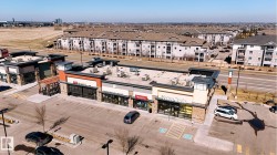 Commercial retail building featuring multiple storefronts, stone veneer accents, flat roofing, and ample surface parking - 