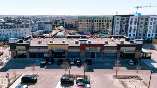 Commercial building with multiple storefronts featuring varied architectural facades, including stone accents and modern paneling - 7226 7327 South Terwillegar Drive, Edmonton, AB - Outdoor