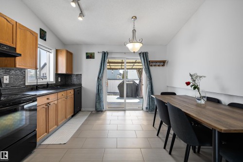 Kitchen and dining area featuring light wood cabinetry, black countertops, and a mosaic tile backsplash - 1811 37 Avenue, Edmonton, AB - Indoor