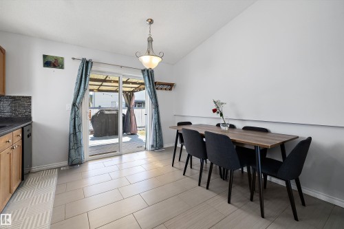 Dining area with vaulted ceiling, wood-finish flooring, and sliding glass doors opening to an outdoor deck - 1811 37 Avenue, Edmonton, AB - Indoor Photo Showing Dining Room