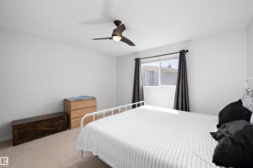Carpeted room with a modern ceiling fan, white walls, and a window with dark curtains - 1811 37 Avenue, Edmonton, AB - Indoor Photo Showing Bedroom