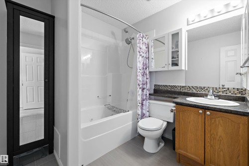 Full bathroom featuring a single vanity with wood-finish cabinetry, a dark countertop, and a tiled backsplash - 1811 37 Avenue, Edmonton, AB - Indoor Photo Showing Bathroom