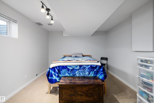 Carpeted room with a ceiling-mounted track light fixture, egress window, white baseboards, and neutral wall paint - 1811 37 Avenue, Edmonton, AB - Indoor Photo Showing Bedroom