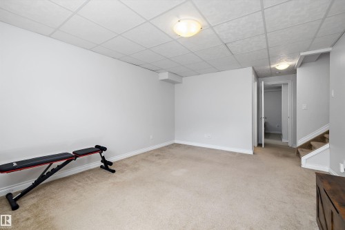 Finished room featuring light-toned carpeting, neutral painted walls, and a drop ceiling with integrated flush-mount lighting - 1811 37 Avenue, Edmonton, AB - Indoor Photo Showing Gym Room
