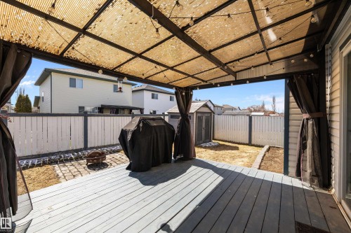 Expansive outdoor deck featuring wood-finish flooring, a permanent overhead shade structure with string lighting, and privacy curtains - 1811 37 Avenue, Edmonton, AB - Outdoor With Deck Patio Veranda With Exterior