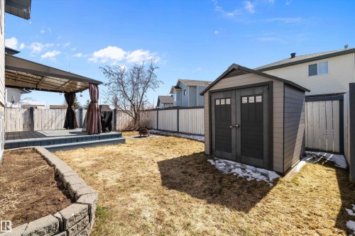 Spacious backyard featuring a multi-level deck with a privacy pergola, a dedicated garden bed with stone retaining wall, and a multi-purpose storage shed - 1811 37 Avenue, Edmonton, AB - Outdoor With Exterior
