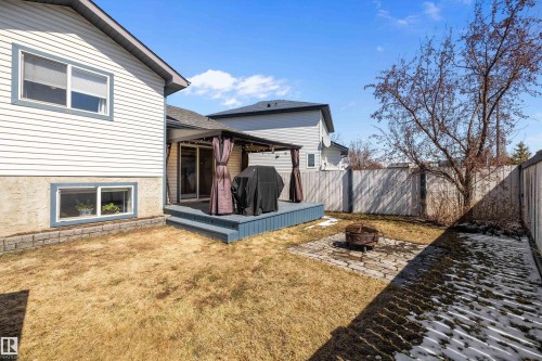 Rear exterior featuring a ground-level deck with a pergola, sliding glass door, and a paver patio with a fire pit - 1811 37 Avenue, Edmonton, AB - Outdoor With Exterior