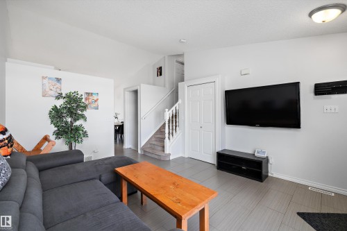 Open-concept living space featuring wood-finish flooring, a wall-mounted television, and a white bi-fold closet door - 1811 37 Avenue, Edmonton, AB - Indoor Photo Showing Living Room