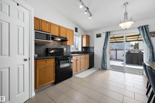 Kitchen featuring wood cabinetry, dark countertops, and a full suite of black appliances - 1811 37 Avenue, Edmonton, AB - Indoor Photo Showing Kitchen