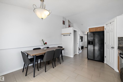 Open concept dining area with light-toned rectangular tile flooring, featuring a contemporary ceiling light fixture - 1811 37 Avenue, Edmonton, AB - Indoor