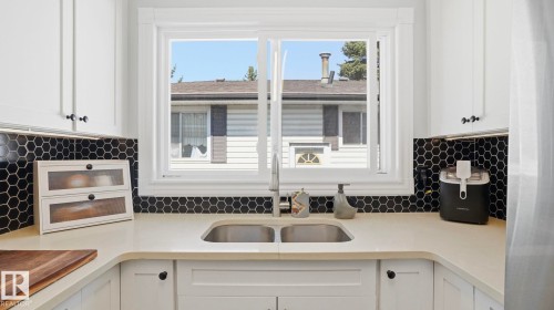 Kitchen sink area featuring a dual-basin stainless steel sink with a gooseneck faucet, set within light-toned countertops - 13533 119 Street, Edmonton, AB - Indoor Photo Showing Kitchen With Double Sink
