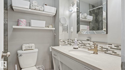 Contemporary bathroom featuring a vanity with an integrated sink, a mosaic tile backsplash, and a decorative mirror - 13533 119 Street, Edmonton, AB - Indoor Photo Showing Bathroom