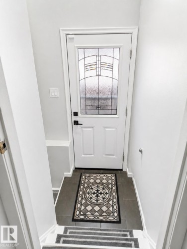 White entry door featuring decorative privacy glass and matte black hardware - 13533 119 Street, Edmonton, AB - Indoor Photo Showing Other Room