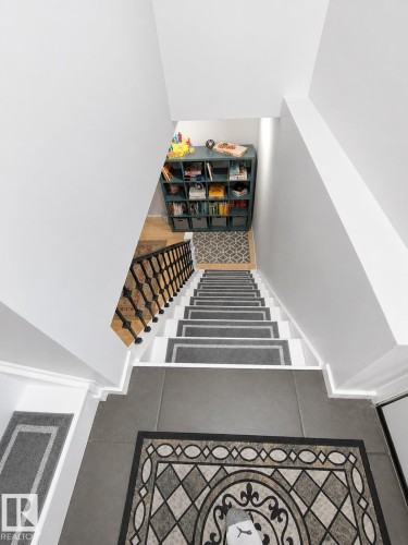 Staircase with white risers and dark gray treads, featuring a black wrought iron railing and wood-finish flooring at the base - 13533 119 Street, Edmonton, AB - Indoor Photo Showing Other Room