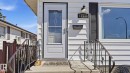 White siding exterior featuring a storm door with decorative glass, black wrought iron handrails, a contrasting black louvered shutter, an exterior wall light, and a prominent house number - 13533 119 Street, Edmonton, AB  - Outdoor 