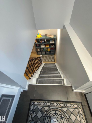Staircase with white risers and dark grey treads, featuring an ornate black metal railing - 13533 119 Street, Edmonton, AB - Indoor Photo Showing Other Room