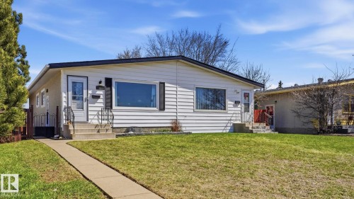 White siding exterior with black trim, featuring two distinct entryways with concrete steps and wrought iron railings - 13533 119 Street, Edmonton, AB - Outdoor