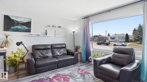 Spacious living area featuring light gray walls, wood-finish flooring, and a large picture window with white trim - 13533 119 Street, Edmonton, AB - Indoor Photo Showing Living Room