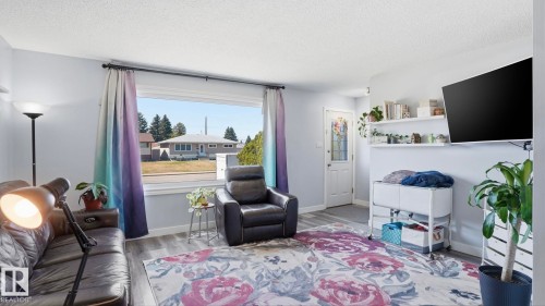 Bright living area featuring a large picture window, wood-finish flooring, and light-toned wall paint - 13533 119 Street, Edmonton, AB - Indoor