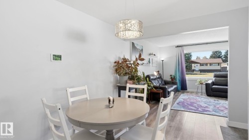 Dining area featuring a contemporary chandelier, light gray walls, and wood-finish flooring - 13533 119 Street, Edmonton, AB - Indoor Photo Showing Dining Room