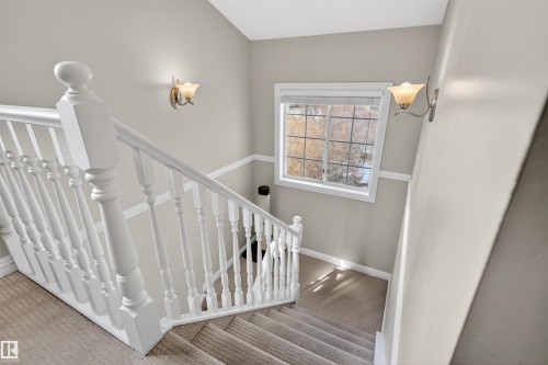 Carpeted staircase with white balusters and handrail, featuring a window and wall sconces providing illumination - 2 Sturgeon Road, St. Albert, AB - Indoor Photo Showing Other Room