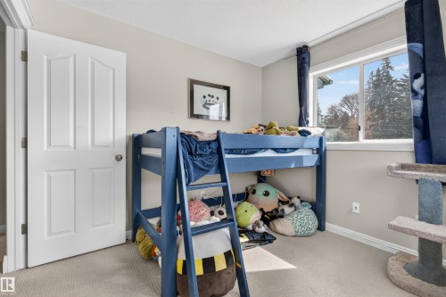 The room features light-colored walls and carpeting, a white paneled door, and a window with white trim - 2 Sturgeon Road, St. Albert, AB - Indoor Photo Showing Bedroom
