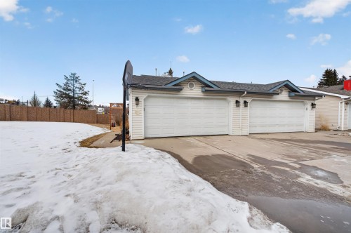The property features a two-car garage with white paneled doors and exterior lighting fixtures - 2 Sturgeon Road, St. Albert, AB - Outdoor