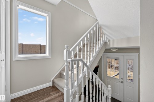 The property features a staircase with white banisters and carpeted treads, a window providing natural light, and a white entry door with glass panes - 2 Sturgeon Road, St. Albert, AB - Indoor Photo Showing Other Room