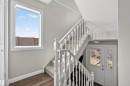 The property features a staircase with white banisters and carpeted treads, a window providing natural light, and a white entry door with glass panes - 2 Sturgeon Road, St. Albert, AB  - Indoor Photo Showing Other Room 