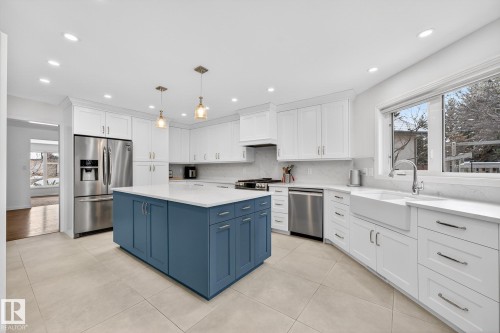 The kitchen features a spacious island with blue cabinetry, white countertops, and stainless steel appliances - 1211 Hewgill Place, Edmonton, AB - Indoor Photo Showing Kitchen With Upgraded Kitchen