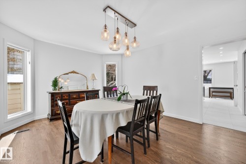 This dining area features wood flooring, a contemporary chandelier, and bright white walls - 1211 Hewgill Place, Edmonton, AB - Indoor Photo Showing Dining Room