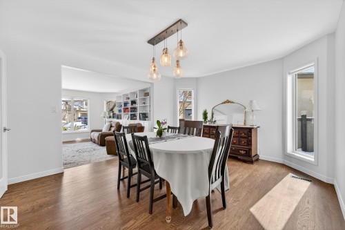 This dining area features hardwood floors and a modern light fixture with clear glass shades - 1211 Hewgill Place, Edmonton, AB - Indoor Photo Showing Dining Room