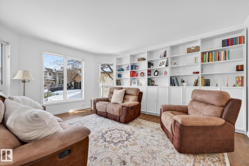 Living area featuring large windows, white walls, and extensive built-in shelving - 1211 Hewgill Place, Edmonton, AB - Indoor Photo Showing Living Room