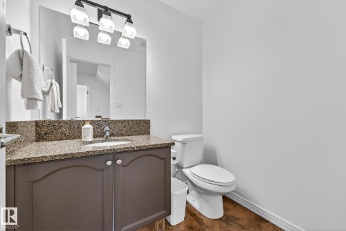 Bathroom featuring a vanity with a granite countertop, a polished chrome faucet, and a large mirror with overhead lighting - 1211 Hewgill Place, Edmonton, AB - Indoor Photo Showing Bathroom