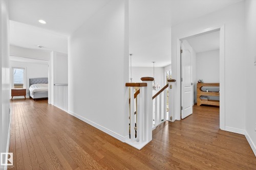 The property features rich hardwood flooring and a staircase with white balusters and a dark wood handrail - 1211 Hewgill Place, Edmonton, AB - Indoor Photo Showing Other Room