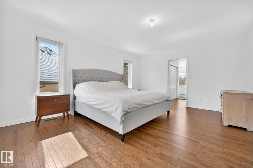This bright bedroom features rich hardwood flooring, white walls, and a window providing natural light - 1211 Hewgill Place, Edmonton, AB - Indoor Photo Showing Bedroom