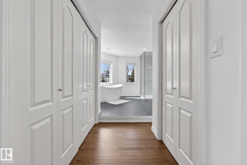 The property features hardwood flooring in the hallway leading to a bathroom with a freestanding tub and a glass-enclosed shower - 1211 Hewgill Place, Edmonton, AB - Indoor Photo Showing Other Room