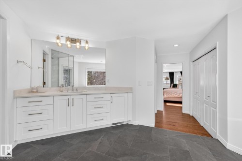 This bathroom features a spacious vanity with white cabinetry and a light-colored countertop - 1211 Hewgill Place, Edmonton, AB - Indoor