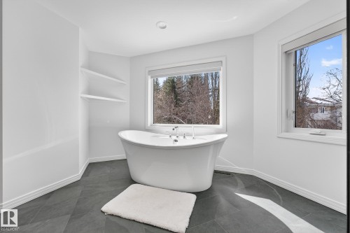 Bathroom featuring a freestanding white bathtub, large windows, recessed lighting, and dark tile flooring - 1211 Hewgill Place, Edmonton, AB - Indoor Photo Showing Bathroom