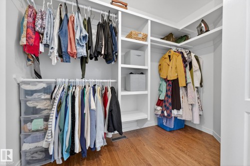 Well-appointed closet space featuring a combination of hanging rods and built-in shelving, complemented by hardwood flooring - 1211 Hewgill Place, Edmonton, AB - Indoor With Storage
