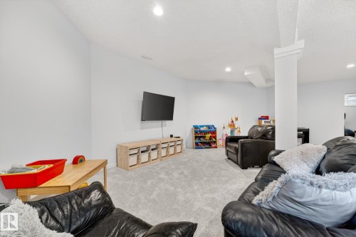 This spacious room features light gray carpeting, recessed lighting, and a white support column - 1211 Hewgill Place, Edmonton, AB - Indoor