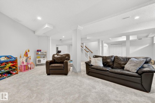 The property features a spacious room with light-colored carpeting, white walls, and recessed lighting - 1211 Hewgill Place, Edmonton, AB - Indoor Photo Showing Living Room