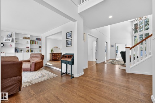 The property features light hardwood floors throughout the main living areas, a white staircase with a wooden handrail, and high ceilings with recessed lighting - 1211 Hewgill Place, Edmonton, AB - Indoor