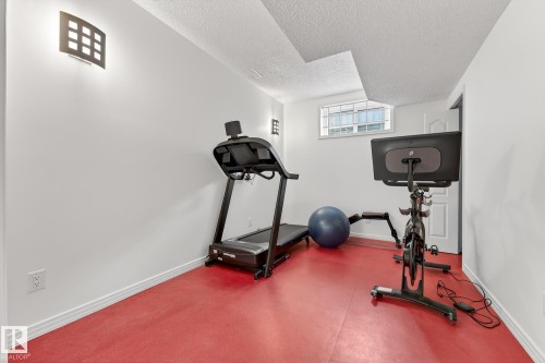 This space features a red floor, white walls, and a window providing natural light - 1211 Hewgill Place, Edmonton, AB - Indoor Photo Showing Gym Room