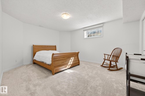 The room features light-colored carpeting, white walls, and a window providing natural light - 1211 Hewgill Place, Edmonton, AB - Indoor Photo Showing Bedroom