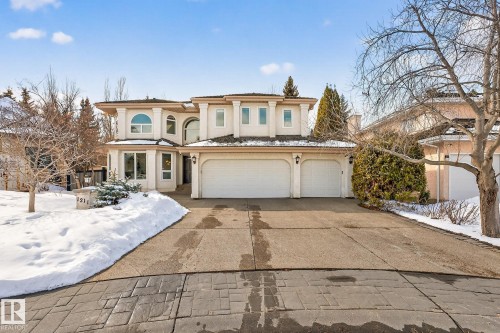 This property features an inviting exterior with a light-colored facade, an arched window, and a two-car garage - 1211 Hewgill Place, Edmonton, AB - Outdoor With Facade