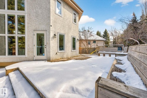 The property features a stucco exterior, large windows, and a glass-paneled door opening onto a wooden deck - 1211 Hewgill Place, Edmonton, AB - Outdoor